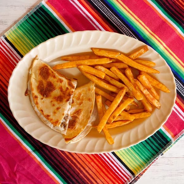 Nunez Foods quesadilla and fries on a white plate, atop a vibrant striped Mexican serape.