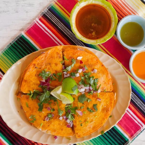 Nunez Foods' quesadillas, garnished with cilantro, red onion, and lime, served with three dipping sauces.
